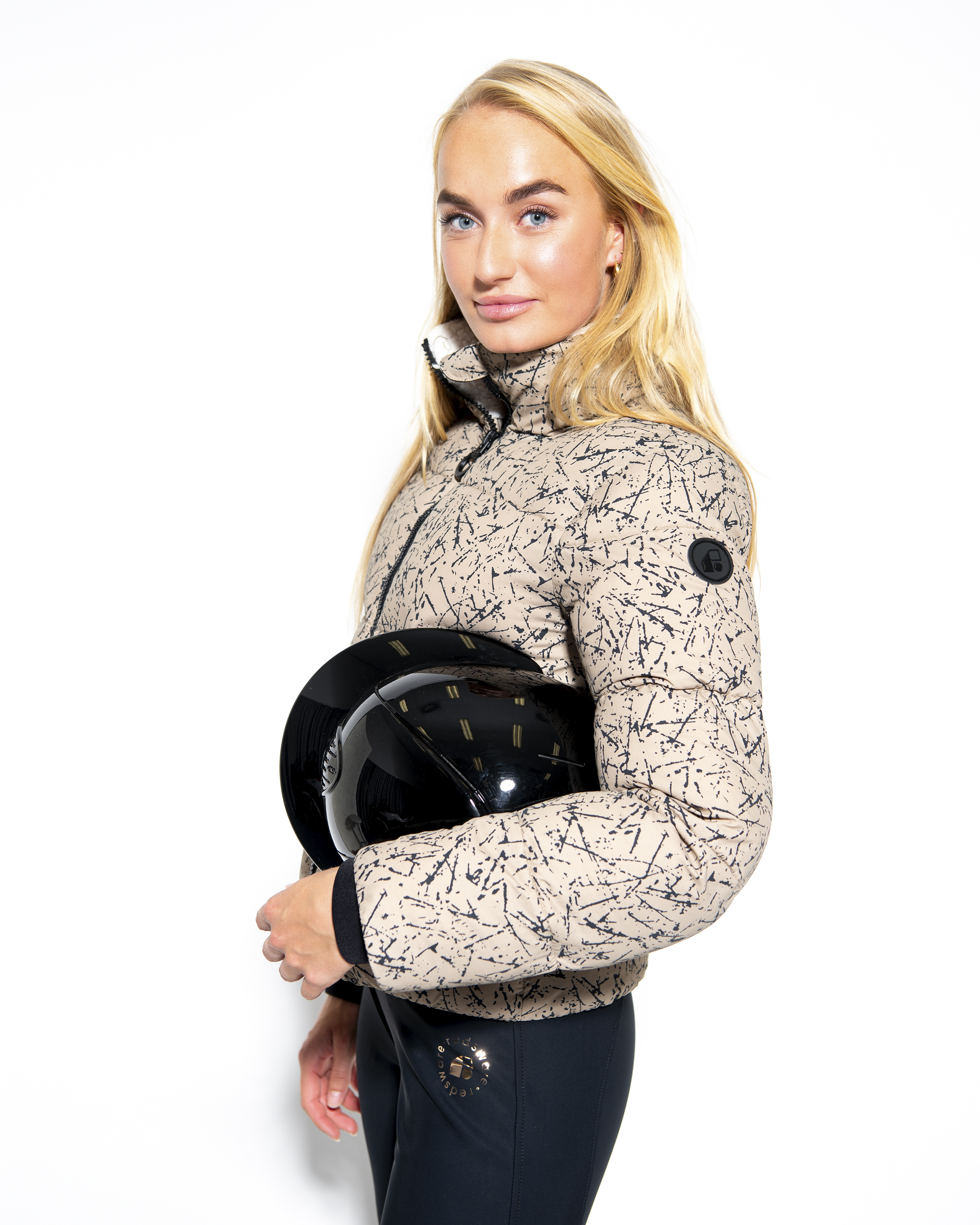 Suzy winter jacket in Mouse, three-quarter view holding a riding helmet